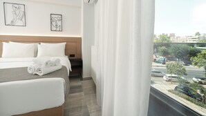 Ein Hotelzimmer mit einem Bett, Kissen, einem gefalteten Handtuch und zwei gerahmten Kunstwerken an der Wand.