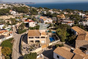 A residential area with a prominent house featuring a swimming pool, a curved driveway, and a view of the sea. - CostaBlancaDreams - Villa Los Pinos in Calpe (Calpe)