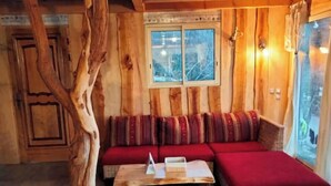 Un interior de madera con un sofá, una mesa y un ventanal.