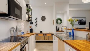 Una cucina moderna con forno a microonde, fornello, lavandino e piani di lavoro in legno.