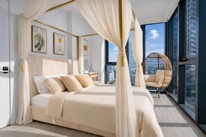 Ein Schlafzimmer mit Himmelbett, Blick auf die Stadt und einem Korbstuhl.