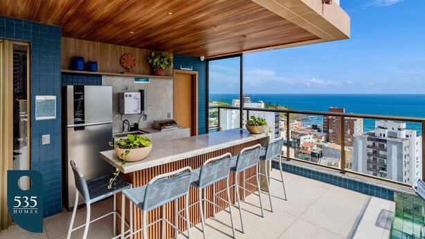 A modern kitchen with a large island, bar stools, and a view of the ocean. - 2 suites on a high floor in Barra with ocean view (Salvador)