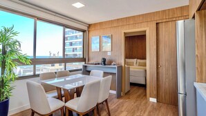 A modern kitchen with a dining area, wooden flooring, and large windows offering a city view. - 2 suites on a high floor in Barra with ocean view (Salvador)