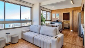 A modern living room with a sofa, a dining area, and a kitchen. - 2 suites on a high floor in Barra with ocean view (Salvador)