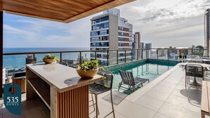A rooftop pool area with a bar, seating, and a view of the sea. - 2 suites on a high floor in Barra with ocean view (Salvador)