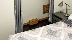 Une chambre avec un lit superposé, une table de chevet avec une lampe et une étagère en bois au-dessus du lit.