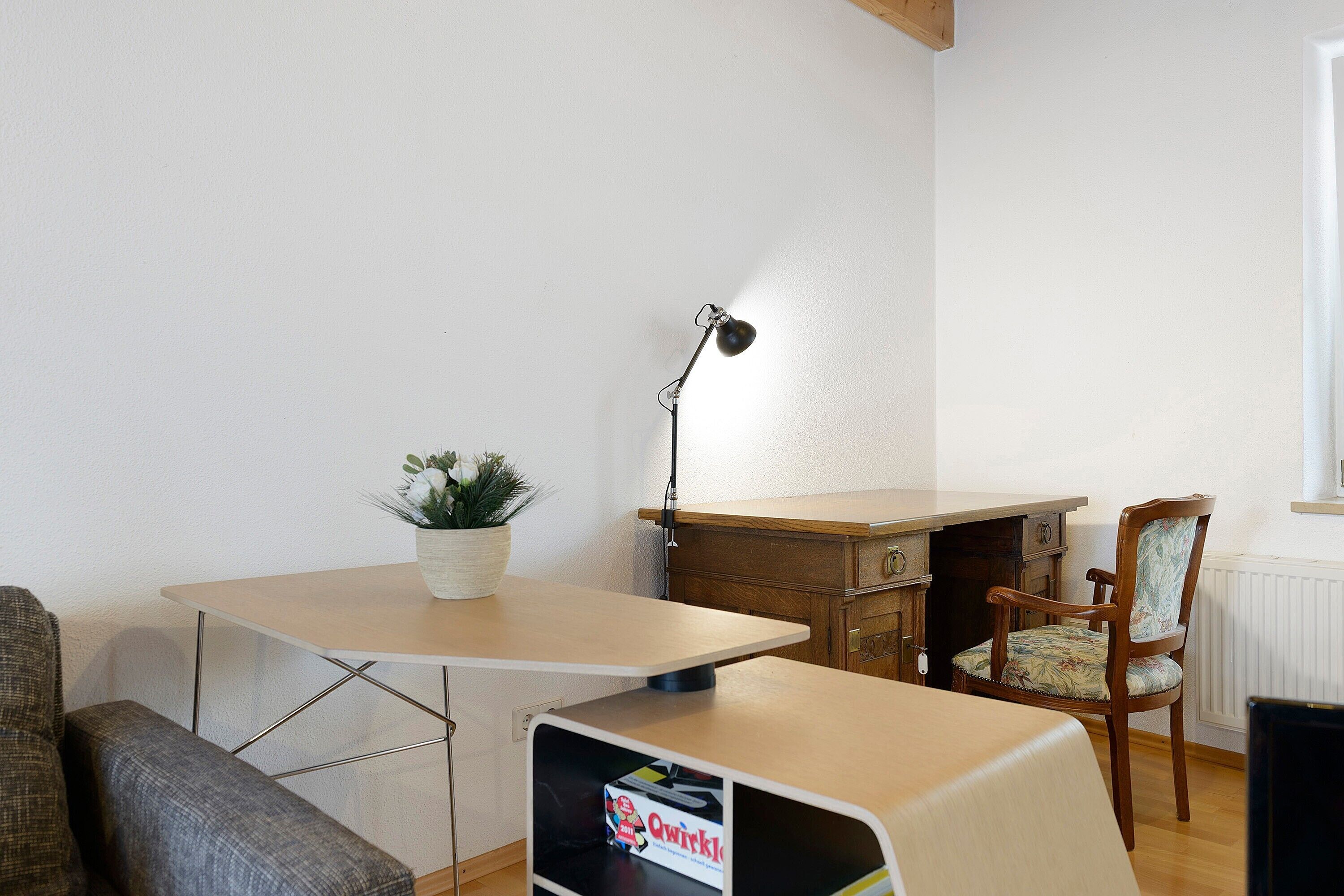Une pièce comprenant un bureau, une chaise et une petite table sur laquelle est posée une plante.