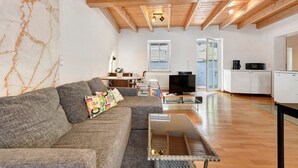 Una sala de estar con sofá, mesa de centro, televisor y una cocina al fondo.