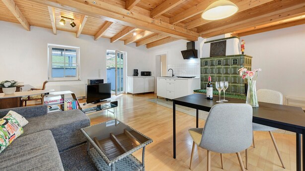 Un amplio espacio de estar con techo de madera, una mesa de comedor, un sofá y una cocina al fondo.