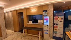 A hotel reception area with a digital kiosk, a bench, and a wall-mounted information board. - Incheon Business Hotel Myung-Jak (Incheon)