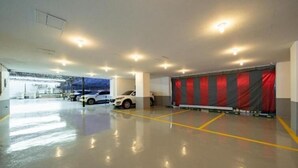 A parking garage with a white car parked near a red curtain. - Incheon Business Hotel Myung-Jak (Incheon)