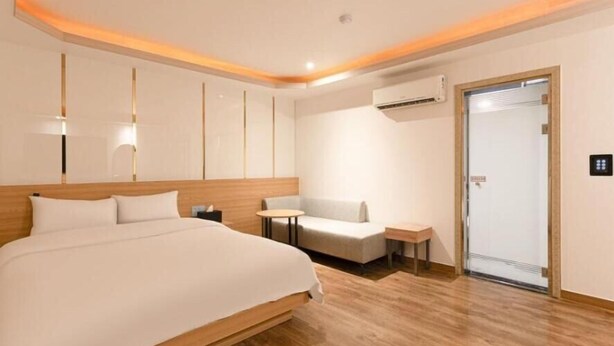 A hotel room with a large bed, a small table, a sofa, and an air conditioning unit. - Incheon Business Hotel Myung-Jak (Incheon)