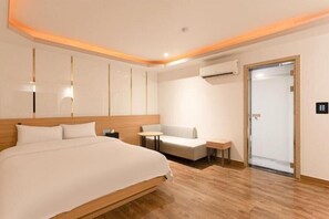 A hotel room with a large bed, a small table, a sofa, and an air conditioning unit. - Incheon Business Hotel Myung-Jak (Incheon)
