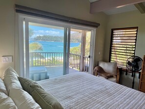 Ein Schlafzimmer mit Bett, Stuhl, Ventilator und Meerblick.