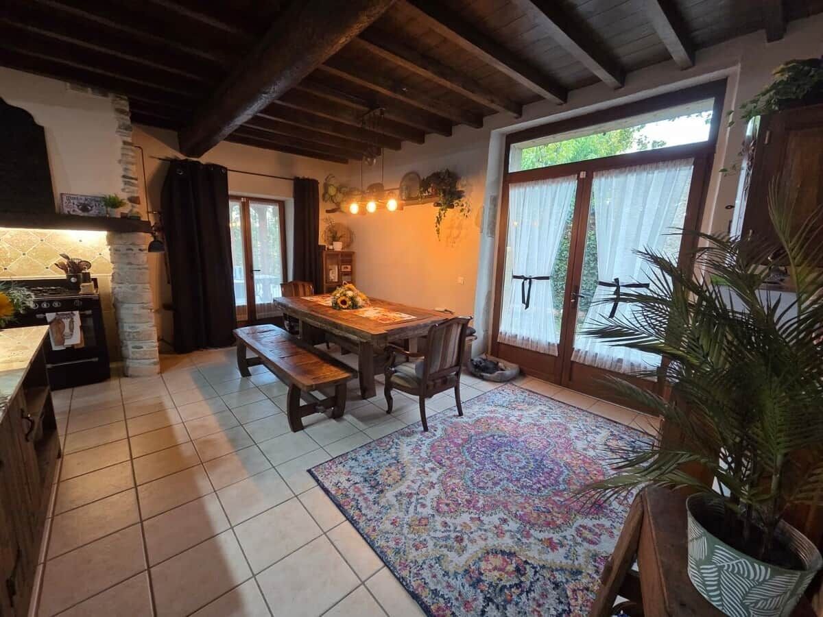 A cozy dining area with a wooden table and benches, a patterned rug, and a stone fireplace.