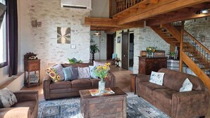 A rustic interior with a wooden staircase, a brown sofa set, and a wooden coffee table with a vase. - Maison la Metairie Trois (Ferran)