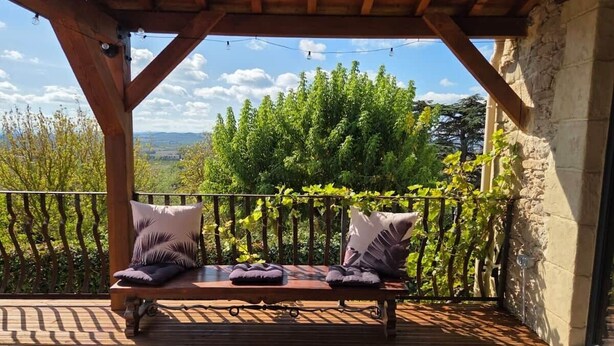 A wooden deck with a bench and cushions, overlooking a lush garden and distant landscape. - Maison la Metairie Trois (Ferran)