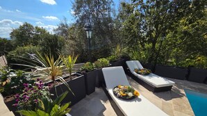An outdoor pool area with two white lounge chairs, a small pool, and surrounding greenery. - Maison la Metairie Trois (Ferran)