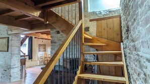 A wooden staircase with a metal railing, leading to a room with stone walls and a wooden ceiling. - Maison la Metairie Trois (Ferran)