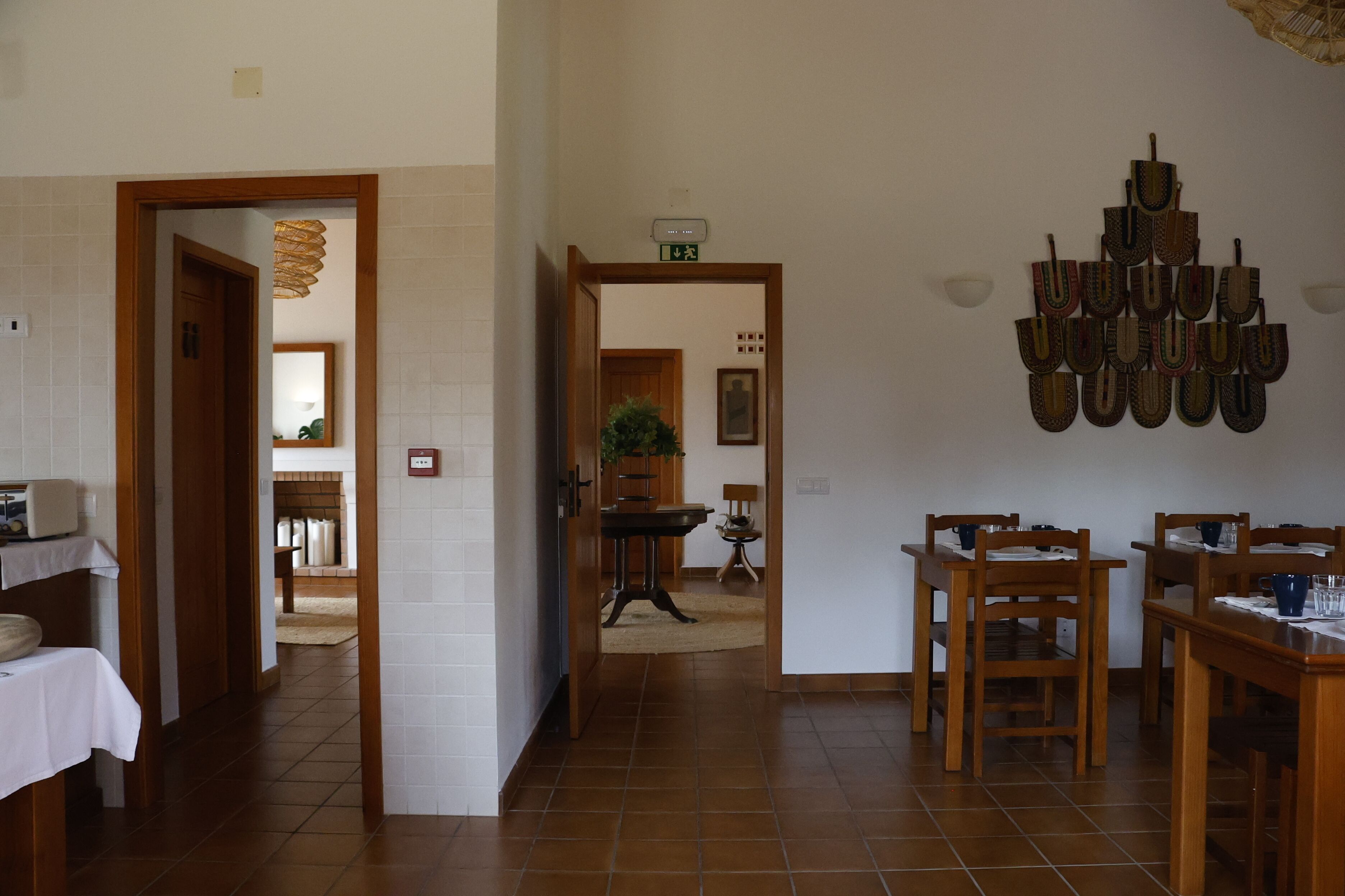 A dining area with wooden furniture, a wall-mounted light fixture, and a tiled floor.