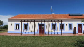 Un edificio con techo de tejas, varias ventanas, una puerta y un panel solar.