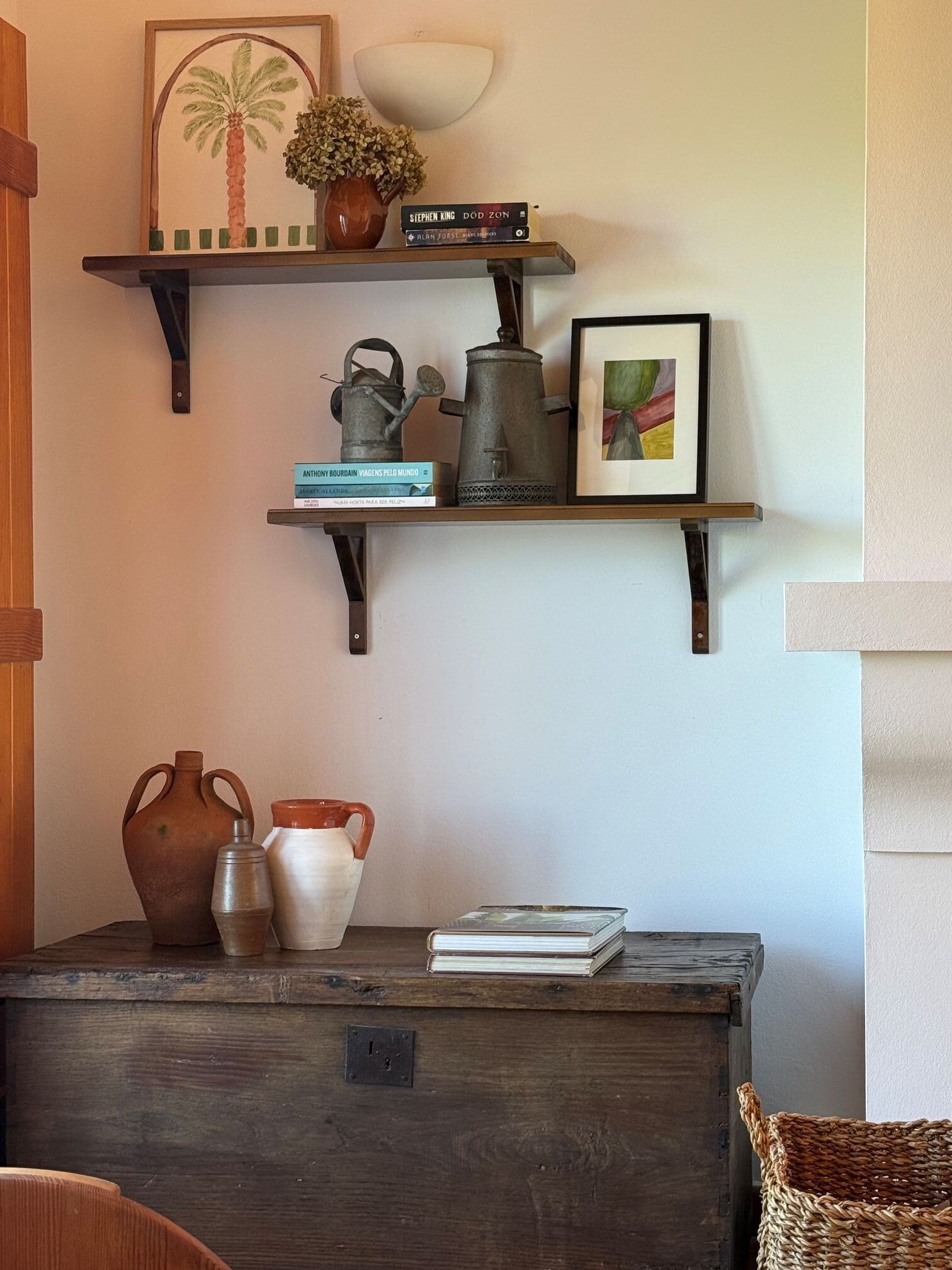 Una estantería de madera con libros, un cuadro enmarcado y adornos.