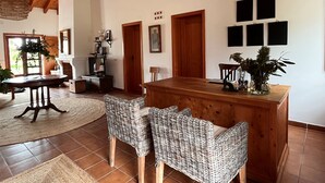 A spacious room with a wooden dining table, wicker chairs, a large woven ceiling light, and a view of the outdoors through a door. - Monte da Estrada - Turismo Rural (Zambujeira do Mar)