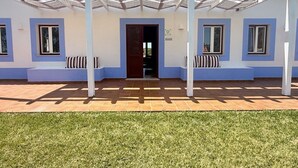 A building with a covered patio, a door, and a small outdoor seating area. - Monte da Estrada - Turismo Rural (Zambujeira do Mar)