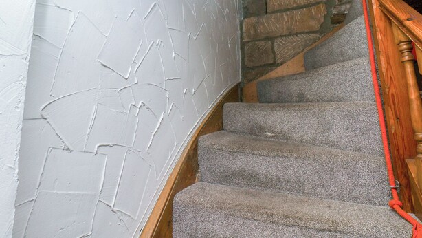 A staircase with stone walls and a wooden handrail. - Bishop's Cottage (Whitby)