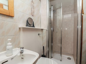 A bathroom with a sink, mirror, and shower. - Bishop's Cottage (Whitby)