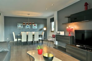 A modern living room with a dining area, a flat-screen TV, and a red vase on a console table. - 5 minutes to Ibiza Town | Pool | Spa Pool (Can Ramon)