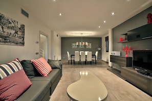 A modern living room with a sofa, coffee table, TV, dining area, and artwork on the wall. - 5 minutes to Ibiza Town | Pool | Spa Pool (Can Ramon)
