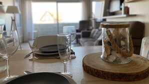 Ett matbord dukat med tallrikar, glas och bestick, en glasburk med snäckskal och en underlägg i trä.