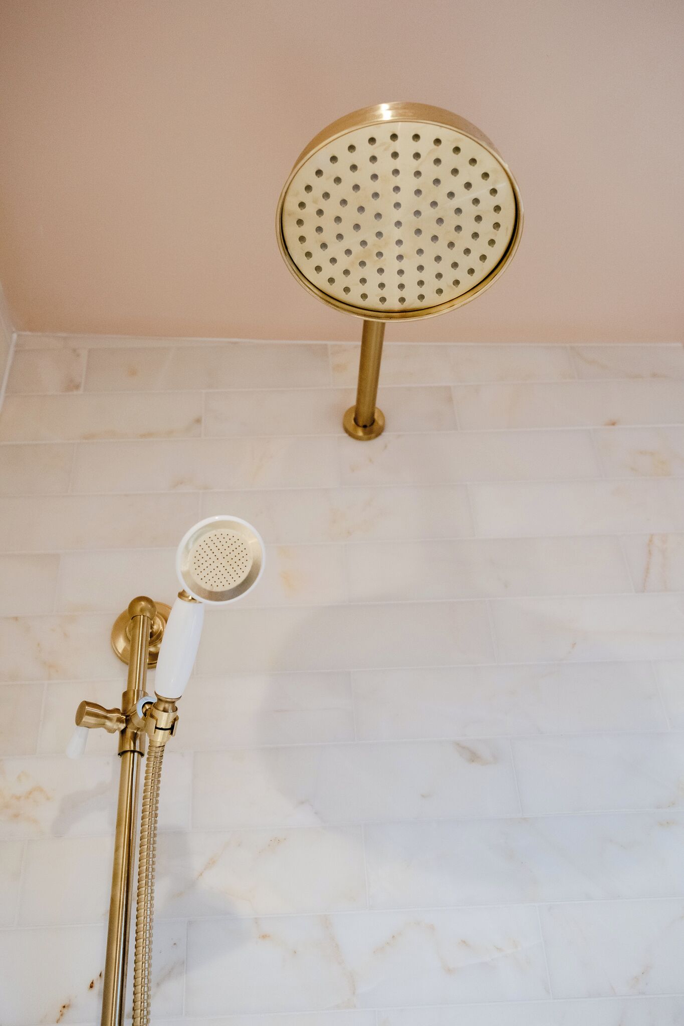 Une salle de bain équipée d’un pommeau de douche doré, d’un pommeau de douche à main et d’un pommeau de douche rond fixé au mur.