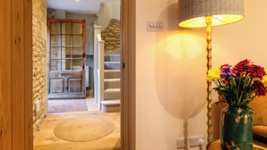 A wooden door leading to a staircase, a lamp, and a vase with flowers. - Sycamore Cottage Banham Cottages (Bourton-on-the-Water)