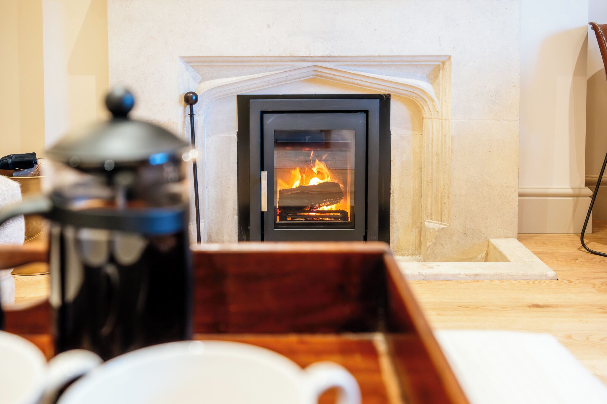 A fireplace with a visible fire, a coffee pot, and a tray with cups.