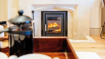 A fireplace with a visible fire, a coffee pot, and a tray with cups.