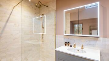 A modern bathroom with a glass shower enclosure, a large mirror, and a white vanity with a sink.