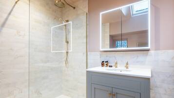 A modern bathroom with a glass-enclosed shower, a vanity with a mirror, and a sink.