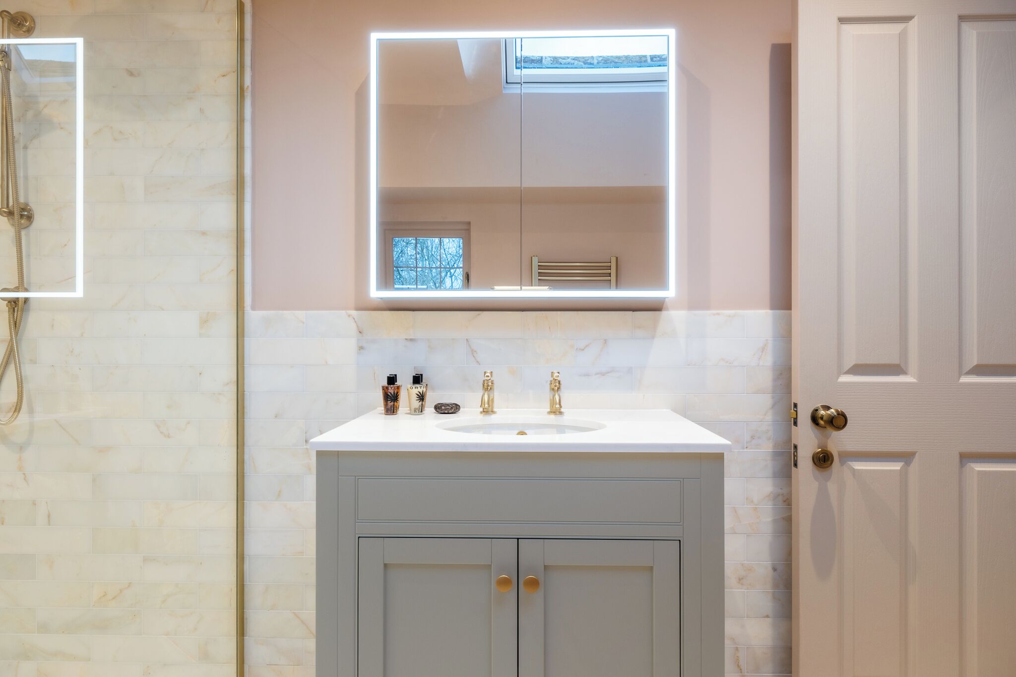 A bathroom with a marble vanity, a large mirror, and a door.