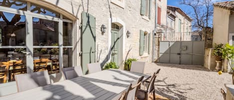 A courtyard with outdoor seating, stone walls, and a gate.