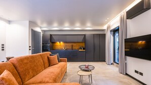 Un salon moderne avec un canapé, une petite table ronde et un coin cuisine à l’arrière-plan.