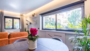 Un salon moderne avec une table ronde, un canapé orange et une plante en pot ornée de fleurs roses.
