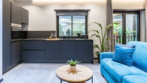A modern kitchen with dark cabinetry, a central island, and a dining area with a blue sofa and a round table. - Santopaolo Boutique Apartment - 4 (Naples)