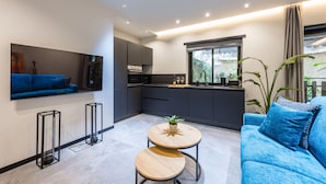 A modern kitchen with dark cabinets, a built-in oven, and a window with a view of greenery. - Santopaolo Boutique Apartment - 4 (Naples)