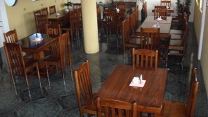 A spacious dining area with multiple wooden tables and chairs, a large pillar, and decorative wall panels. - HOTEL Y RESTAURANTE MAYALAND (Quetzaltenango)