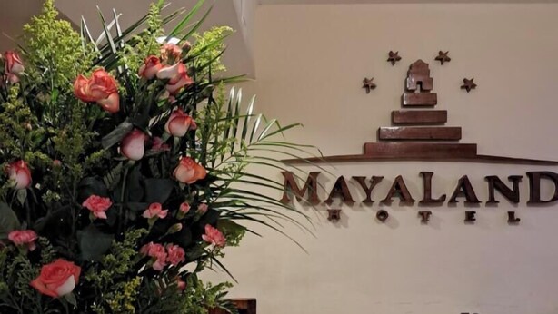 A reception desk with a large floral arrangement, a sign for Mayaland Hotel, and a small wooden structure on the wall. - HOTEL Y RESTAURANTE MAYALAND (Quetzaltenango)