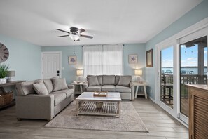 A living room with a sofa, coffee table, and a ceiling fan. - Lagoon Front Living Steps to Beach + Dock + Pool (Gulf Shores)
