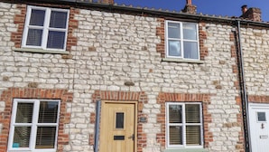 Un bâtiment en pierre avec une porte en bois, de nombreuses fenêtres et une cheminée.