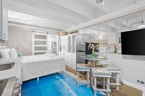 Une cuisine moderne avec des meubles blancs, un réfrigérateur encastré et une table de salle à manger ronde, accompagnée de tabourets de bar.